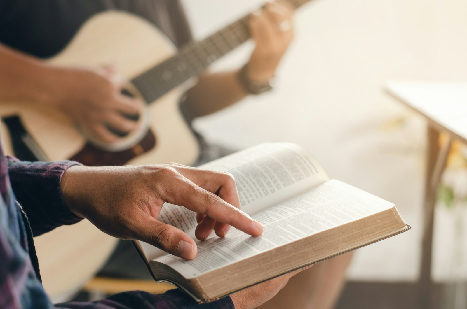 A young boy sat and read the Bible while his friend played guitar at church when he worshiped God.